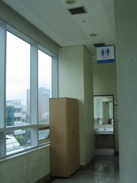 엘리베이터 옆의 화장실로 들어가는 입구. 천장에 새로 설치한 환풍 시설이 보인다. 이 화장실을 이용하기 위해서는   담배연기를 뚫고 지나가야 한다.